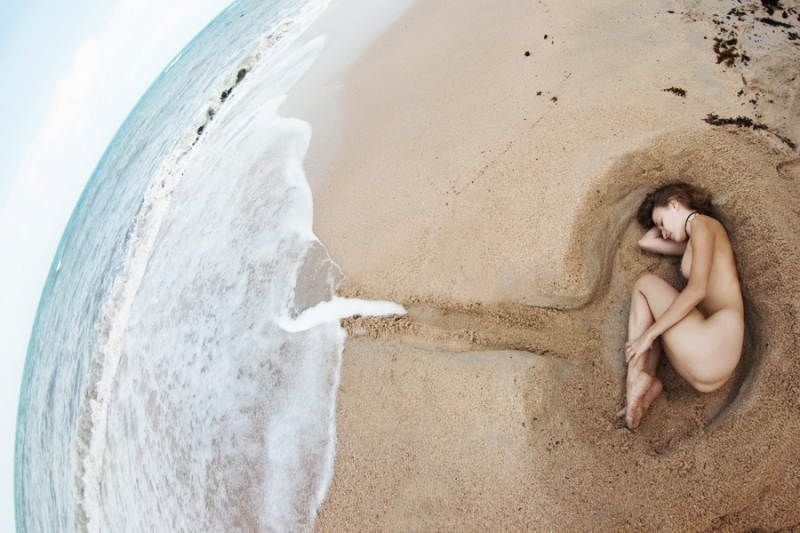 Девушка лежит берегу океана в яме формы утробы. Сиамский залив, остов Самуи (Таиланд)